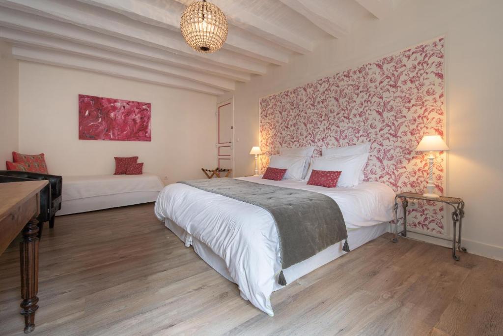 Un dormitorio con una gran cama blanca y una pared en Le Clos de La Rousselière B and B, en Francueil