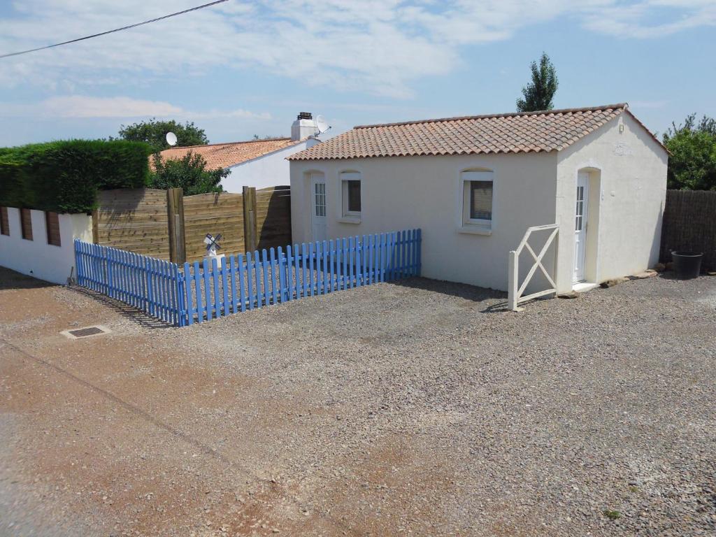 una pequeña casa blanca con una valla azul en Le Moulin à Rêves en Talmont