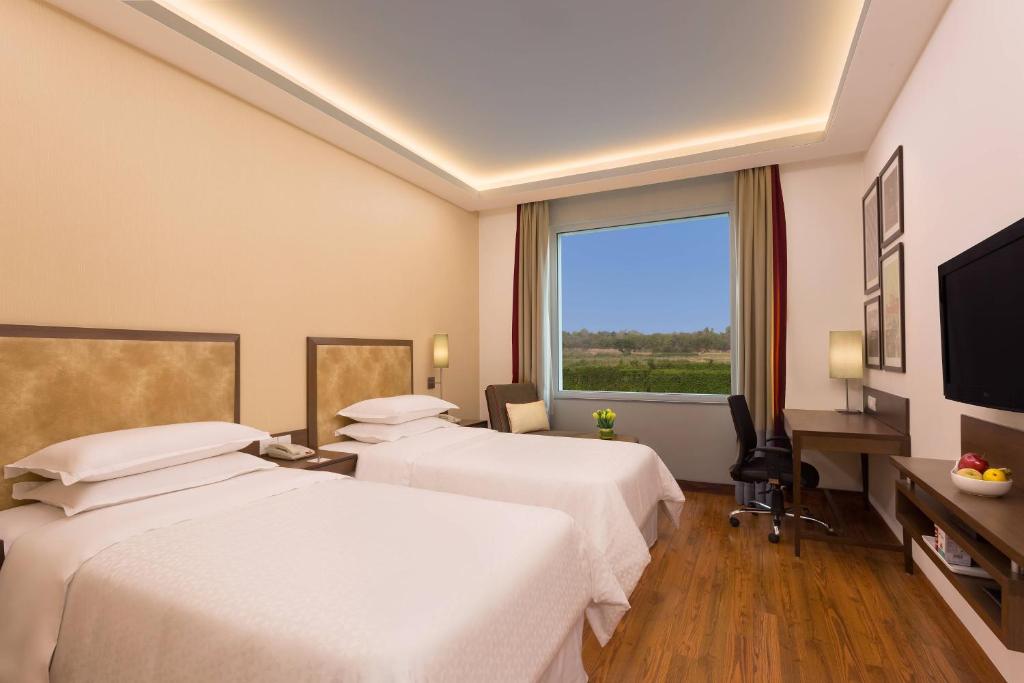 a hotel room with two beds and a large window at Four Points by Sheraton New Delhi, Airport Highway in New Delhi