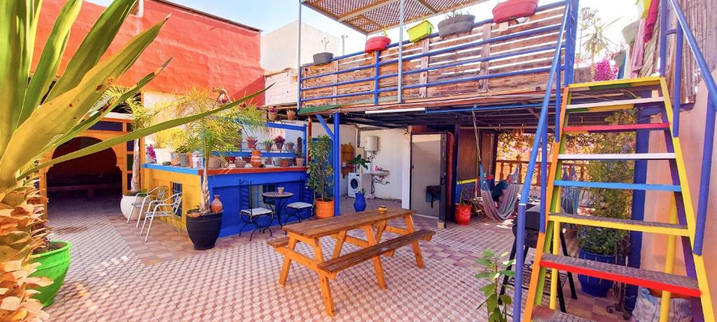 un edificio con un banco en un patio con plantas en Sunset Surfhouse Morocco en Tamraght Ouzdar