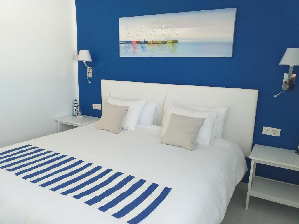 ein Schlafzimmer mit einem weißen Bett und einer blauen Wand in der Unterkunft Apartment La Vela Azul -POOL & TENNIS - free AC &Good WIFI- Smart TV in Puerto del Carmen