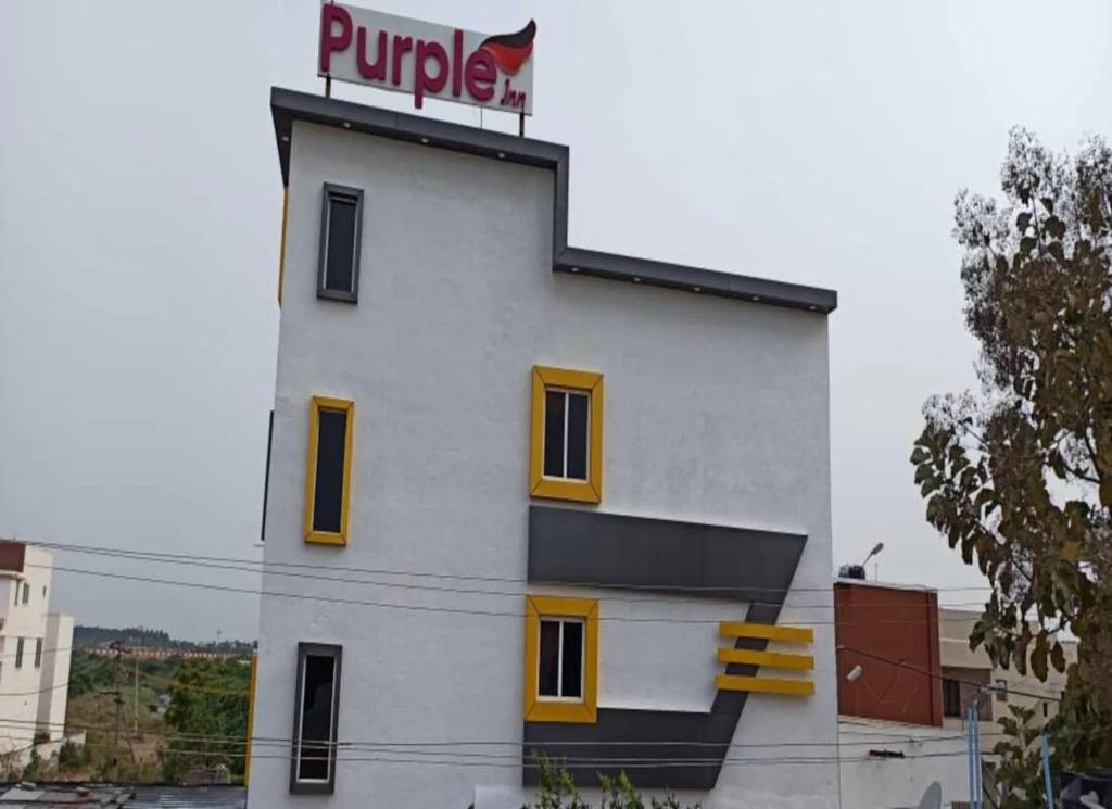 a white building with a purple sign on top of it at Purple Inn in Coimbatore