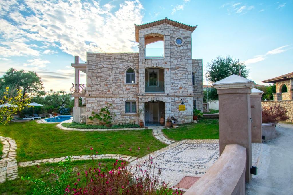une grande maison en pierre avec une cour et une piscine dans l'établissement Villa Olga, à Kalamaki