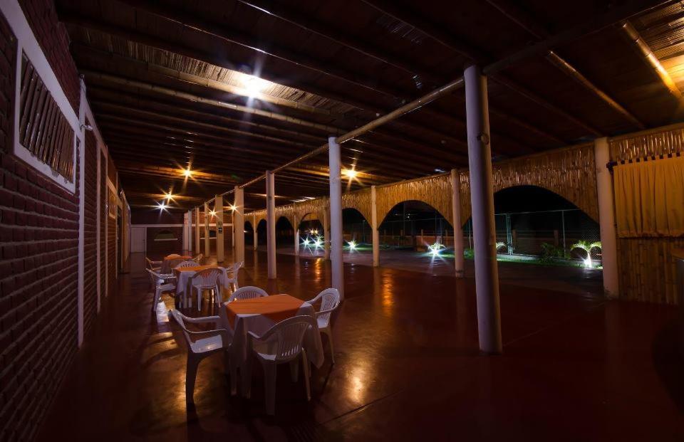 a row of tables and chairs in a building at night at Mancora y Sol in Máncora