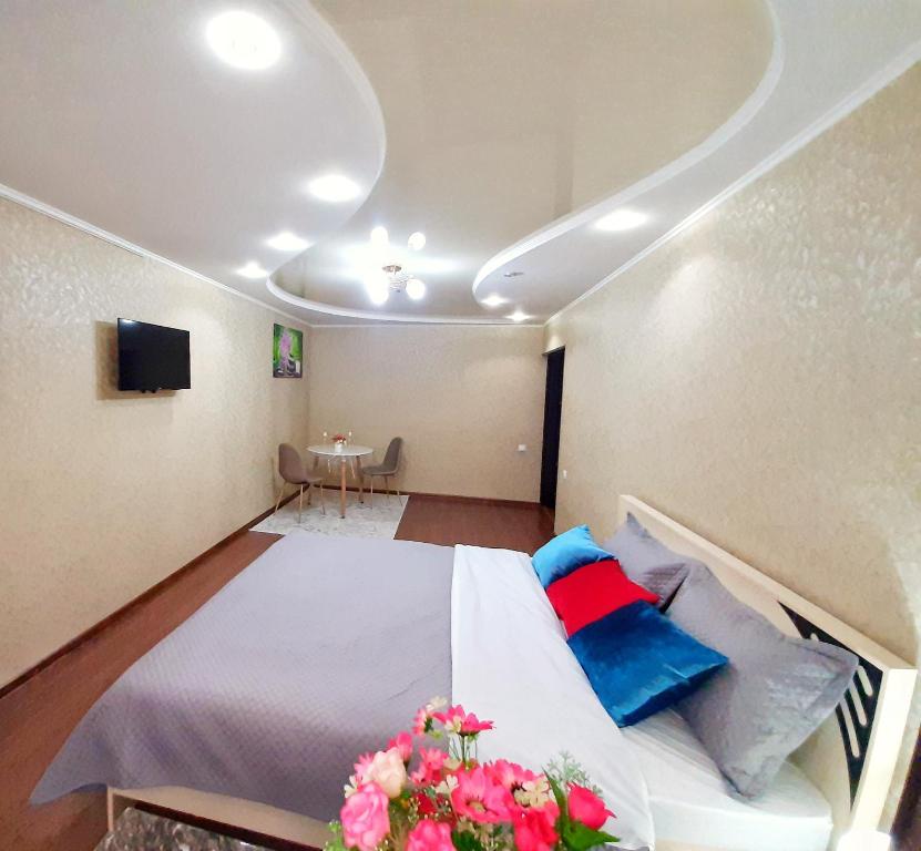 Schlafzimmer mit einem Bett mit blauen und roten Kissen in der Unterkunft Уютная квартира класса ЛЮКС в городе Тараз in Taras