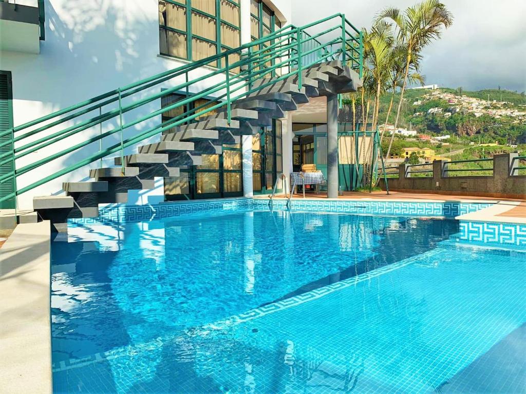 uma grande piscina com uma escada ao lado de um edifício em Eden Villa - Pool, Barbecue, Spectacular Views, 4 Bedrooms - Up to 10 guests ! no Funchal