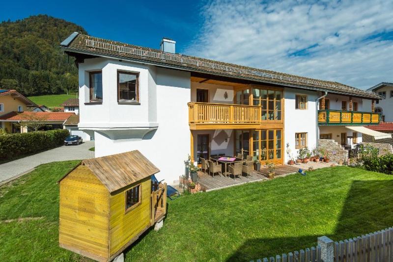 una gran casa blanca con un perro amarillo en el patio en Ferienhaus Am Steinbach en Ruhpolding
