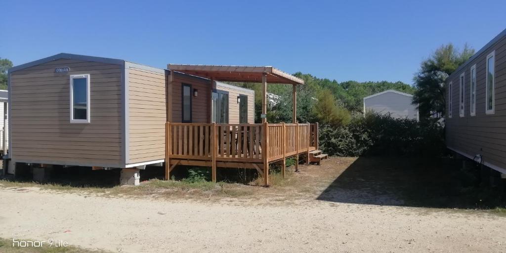 een tiny house met een veranda en een terras bij CAMPING LE SOLEIL D'OR in Vendays-Montalivet