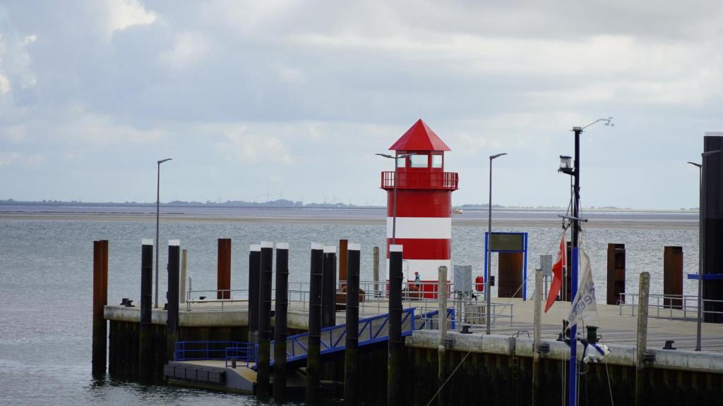 einem roten und weißen Leuchtturm auf einem Dock im Wasser in der Unterkunft Haus Gud Hööb Whg 02 in Wyk auf Föhr