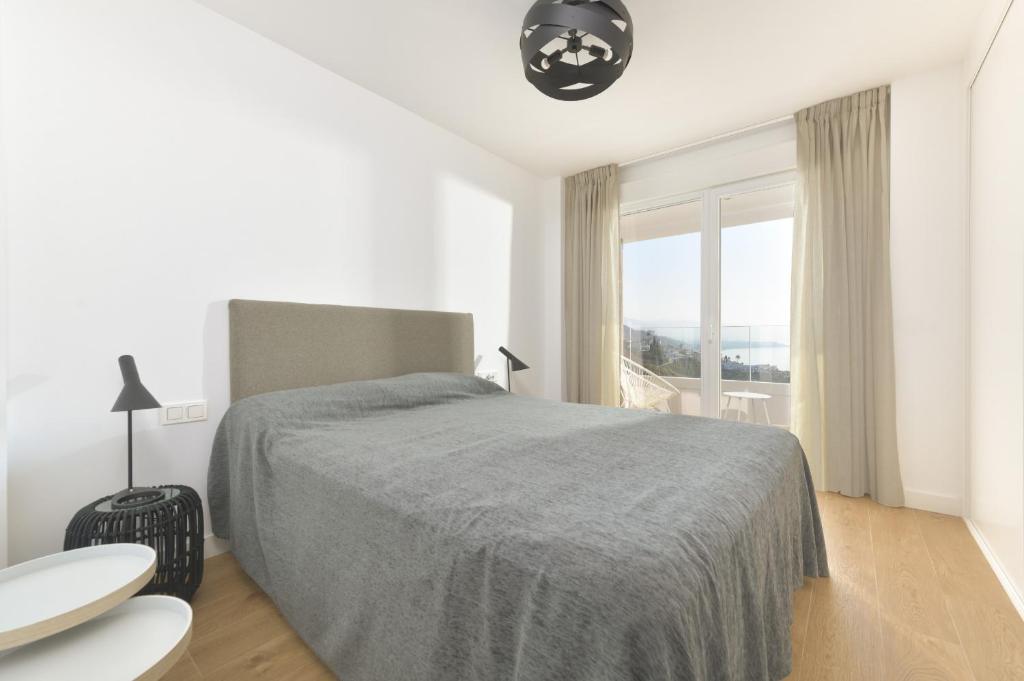 biała sypialnia z łóżkiem i oknem w obiekcie Amplio apartamento vista mar frontal w mieście Torrox Costa