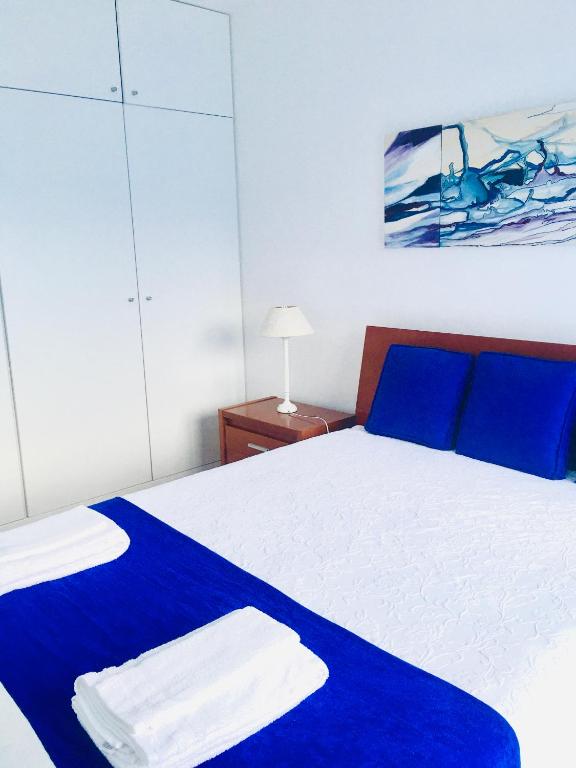 a bedroom with a blue and white bed with blue pillows at Apartamento Vitória in Praia da Vitória
