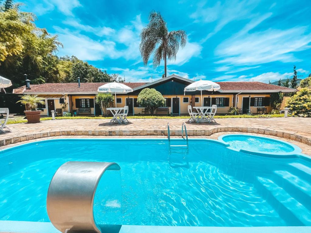 a swimming pool in front of a house at Pousada Flor de Ipe in São Bento do Sapucaí