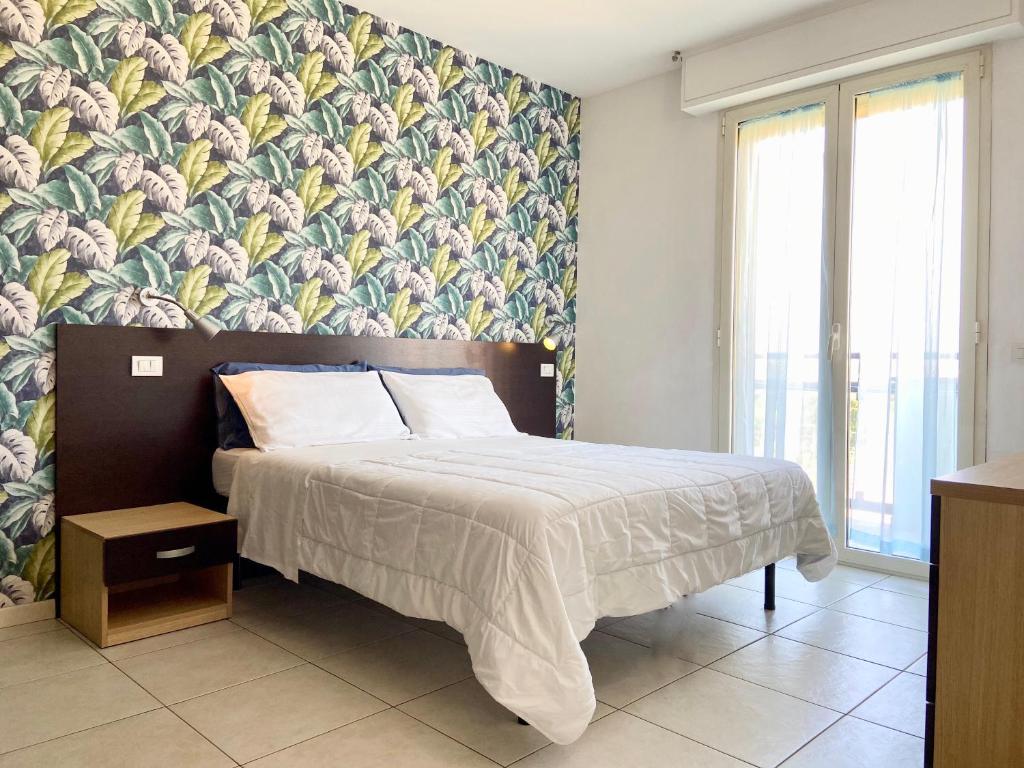 1 dormitorio con 1 cama con papel pintado tropical en Residence Acqua Suite Marina, en Rímini