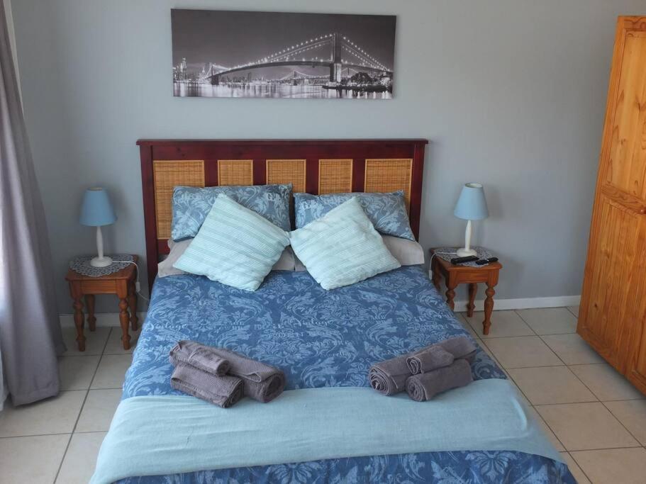 a bed with a blue comforter with towels on it at Heron Place sunny self-catering garden flatlet in Port Alfred