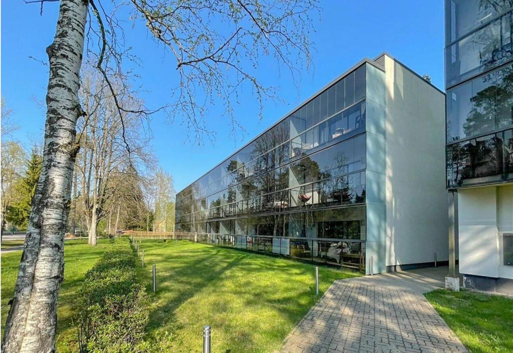 un gran edificio de cristal con un árbol delante de él en Sand Beach Apartment en Narva-Jõesuu