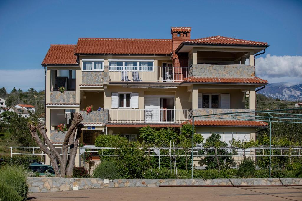 a large house with a red tile roof at Apartmani Ana & Milo in Lopar