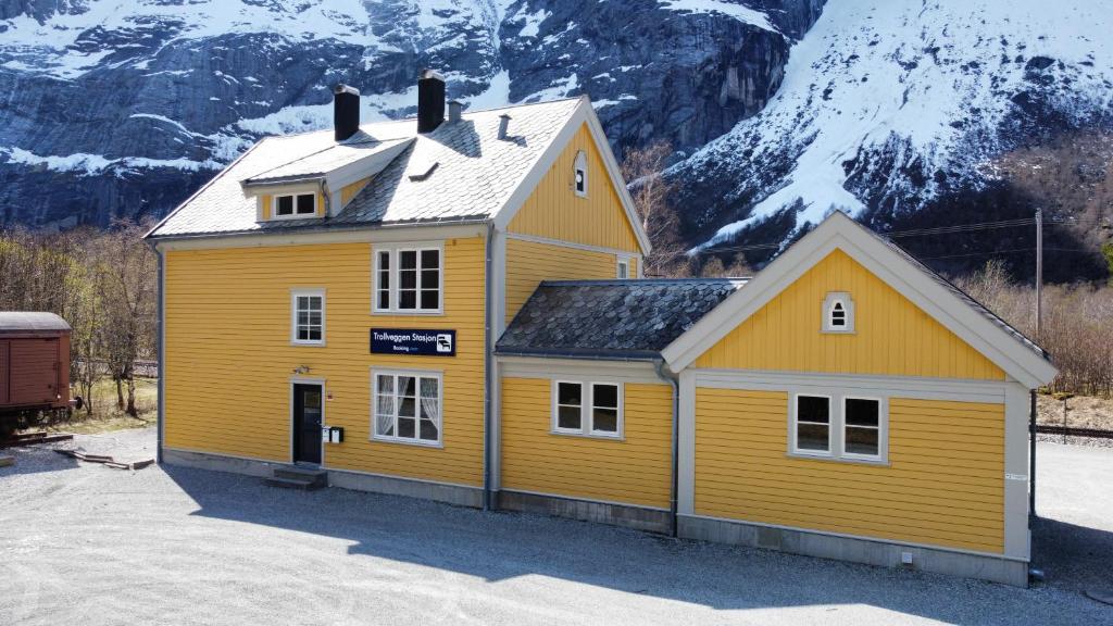a yellow building with a mountain in the background at Trollveggen Stasjon in Åndalsnes