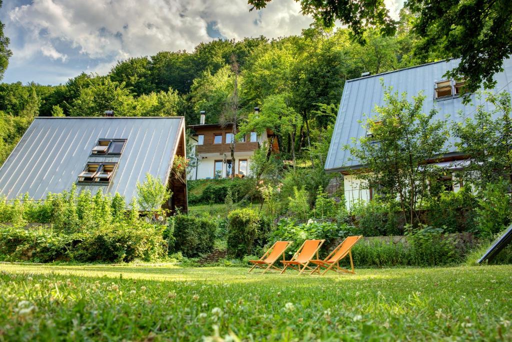 a group of chairs sitting on a lawn in front of a house at Herzegovina Lodges Boracko Jezero in Konjic