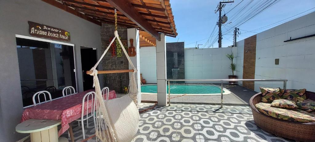 a porch with a swing and a swimming pool at BEACH HOUSE ARUANA in Aracaju