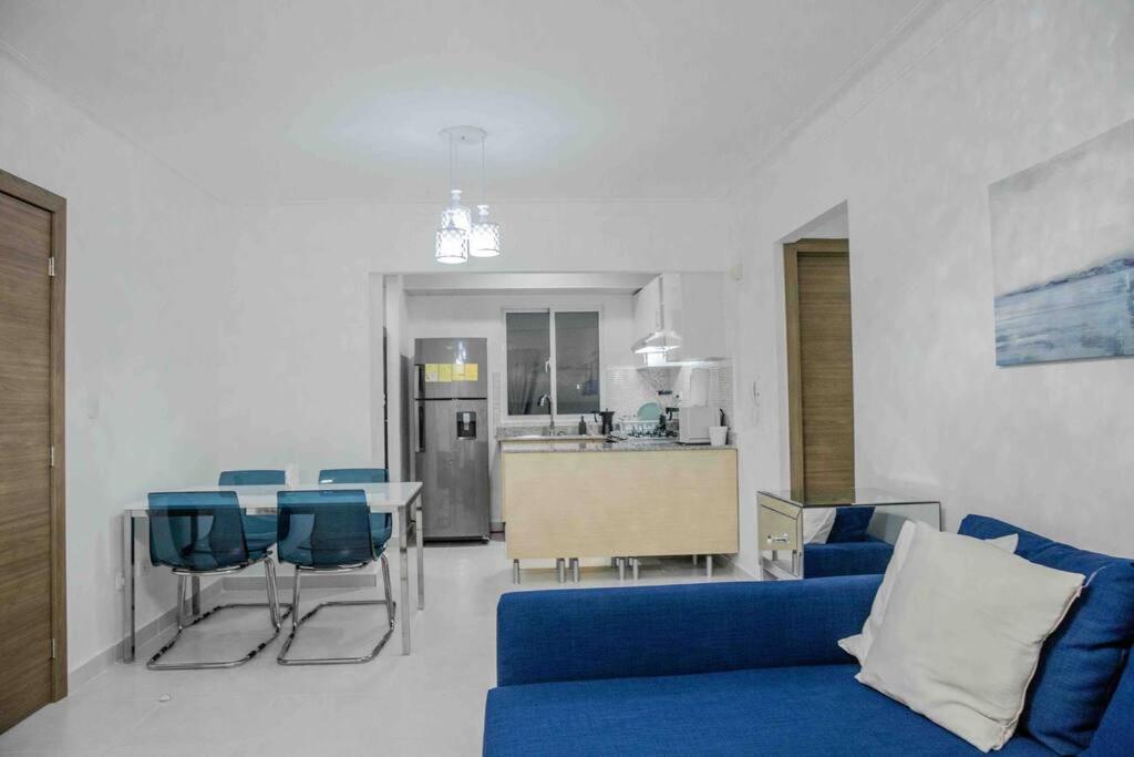 sala de estar con sofá azul y cocina en Lovely condo 10 minutes from airport 15 from beach en La Cana