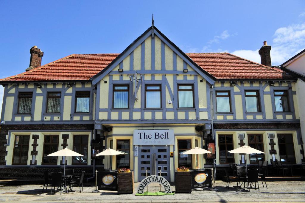 un edificio con mesas y sombrillas delante en The Bell Guesthouse, en Peterlee