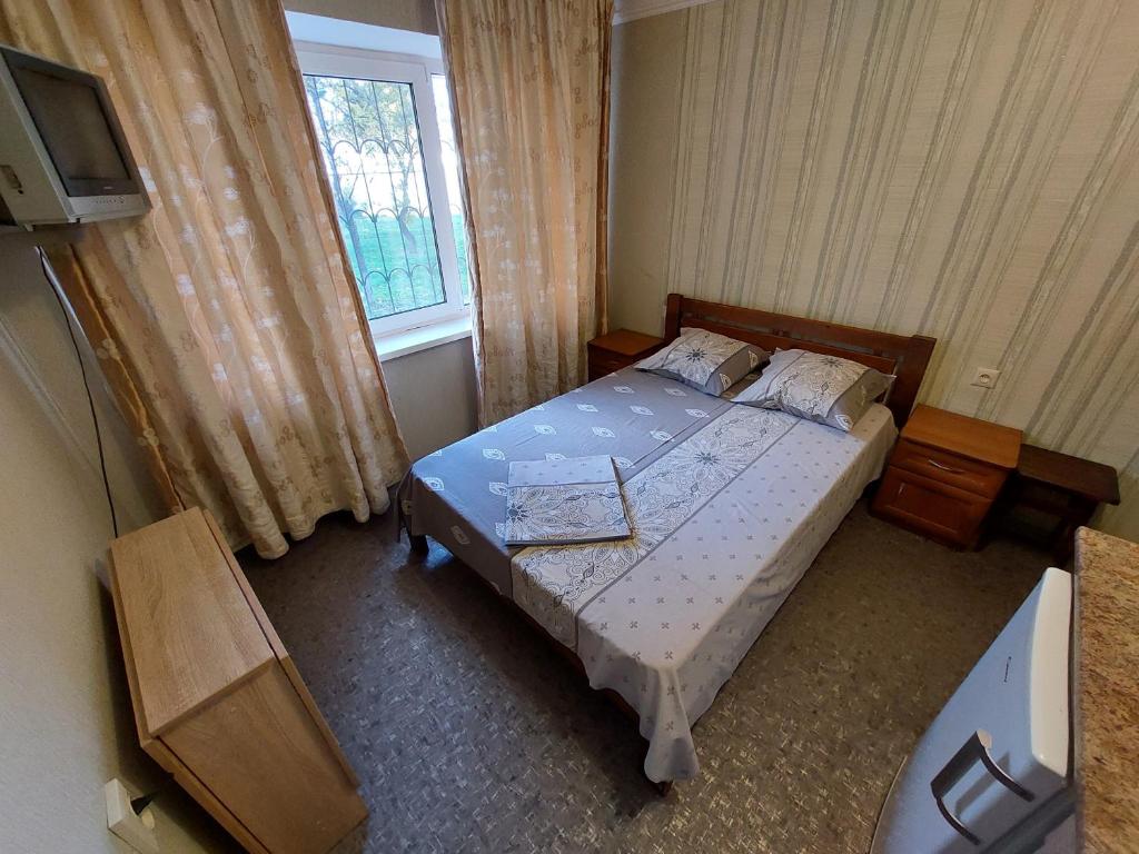 um pequeno quarto com uma cama e uma televisão em Отель Юность em Kiev