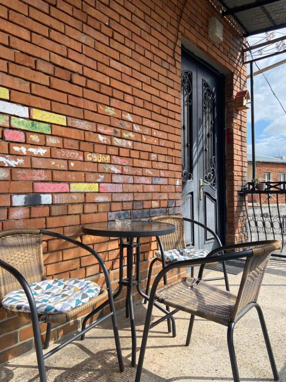 two tables and chairs on a patio with a brick wall at Onestep in Kutaisi