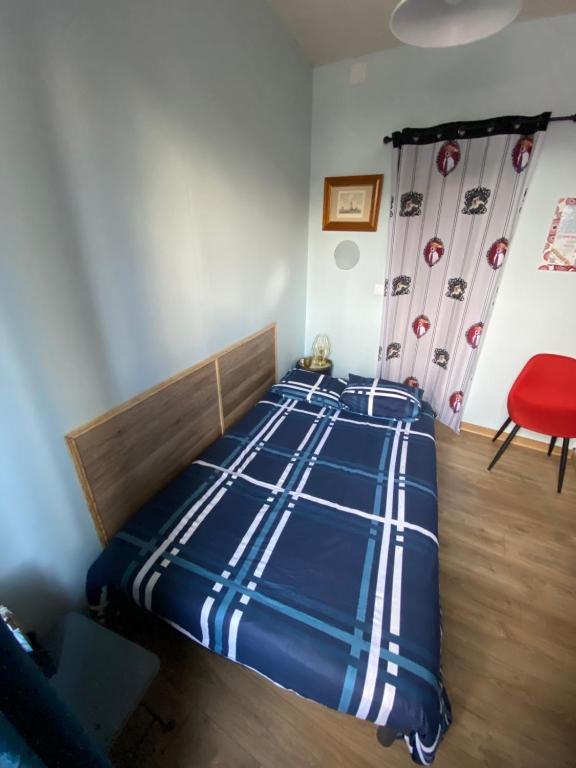 Sympathique logement en rez-de-chaussé, de 21m 2 في بوفيه: غرفة نوم بسرير ازرق مع كرسي احمر