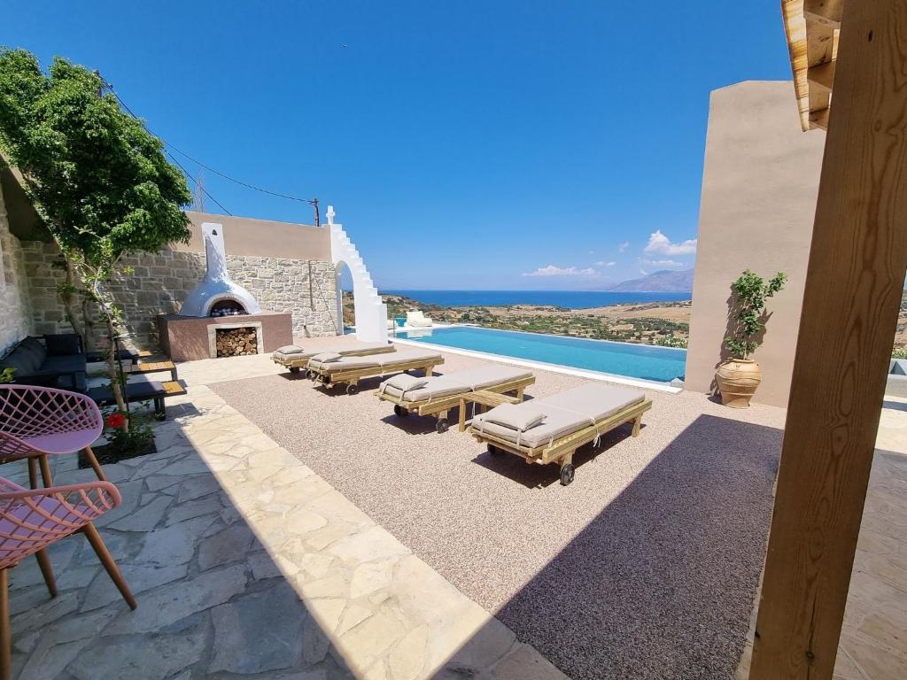 une terrasse avec des chaises longues et une piscine dans l'établissement Villa Grabella-Amazing sea view and swimming pool, à Pitsidia