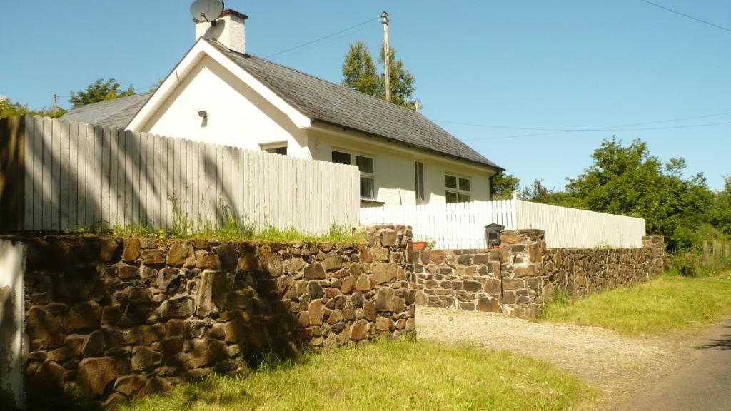 una cerca de piedra frente a una casa en Craigalappan Cottages Holiday Home, en Bushmills