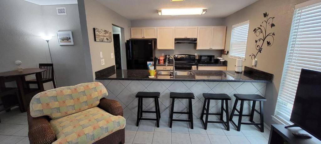 a kitchen with a bar with stools and a couch at Less Than Block to Beach Trinity House-plex I unit 302 in South Padre Island