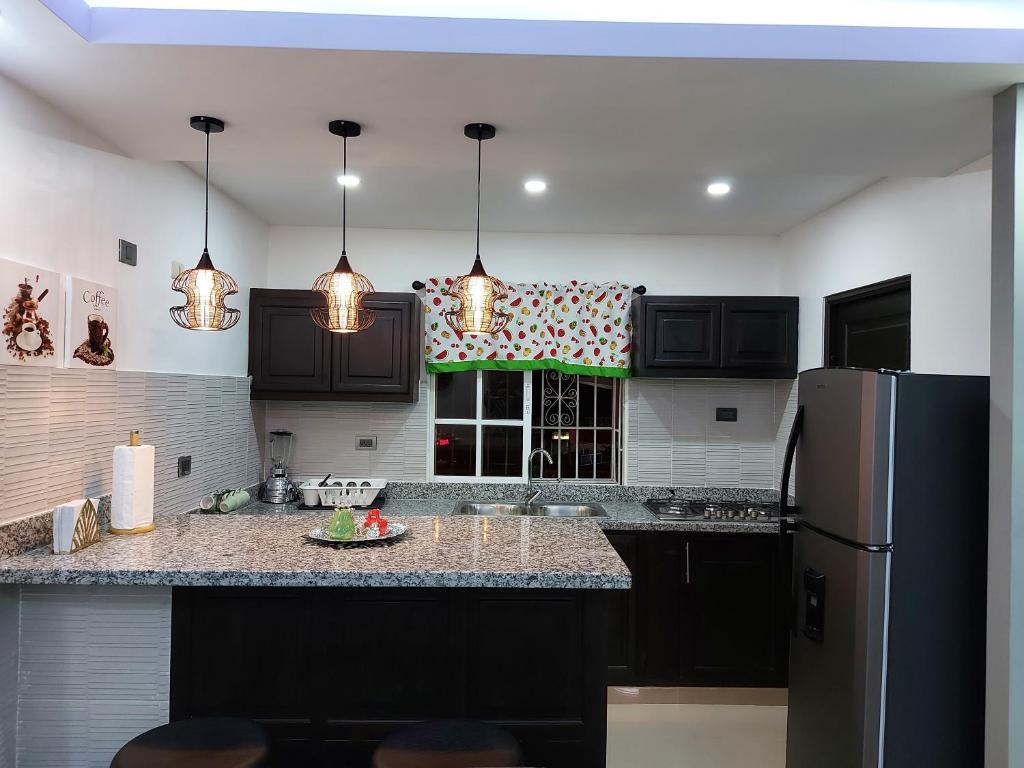 a kitchen with black cabinets and a refrigerator at 4to nivel 2 habitaciones 2 baños Alma Rosa I in El Seis