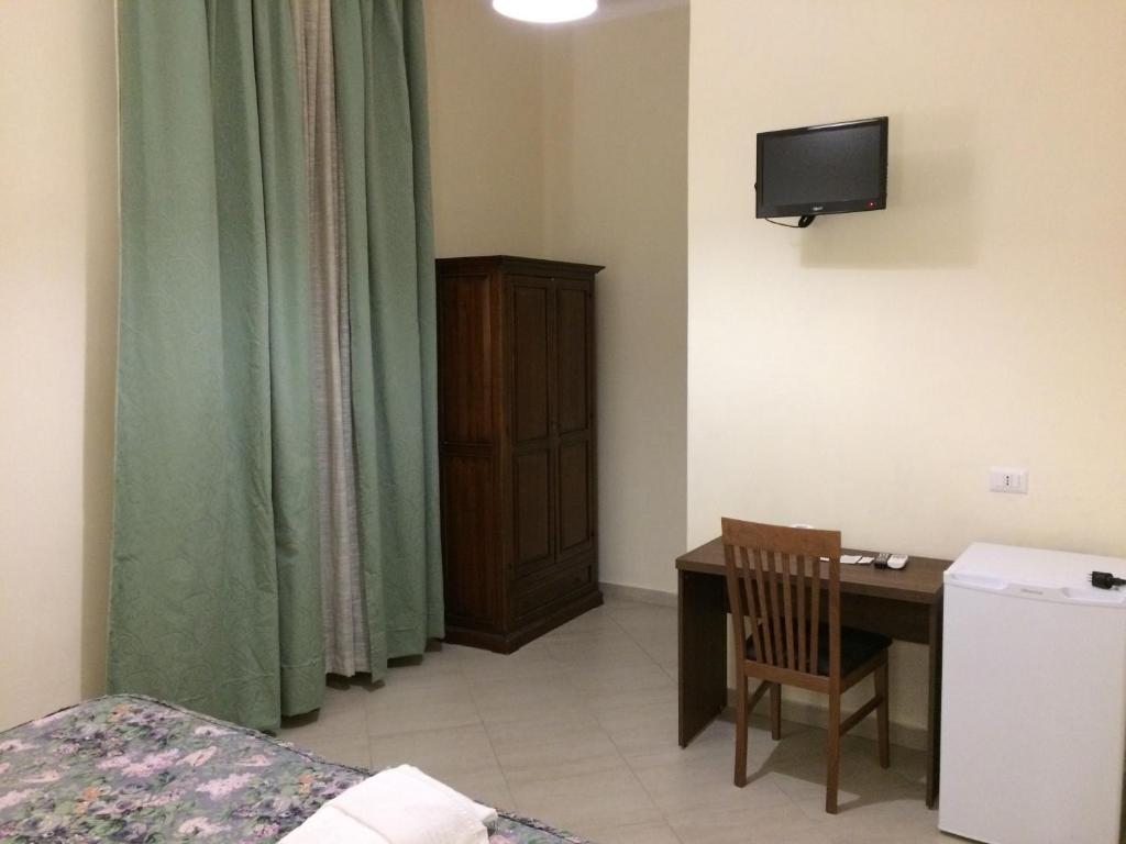 um pequeno quarto com uma secretária e uma televisão em Albergo Enrica em Roma
