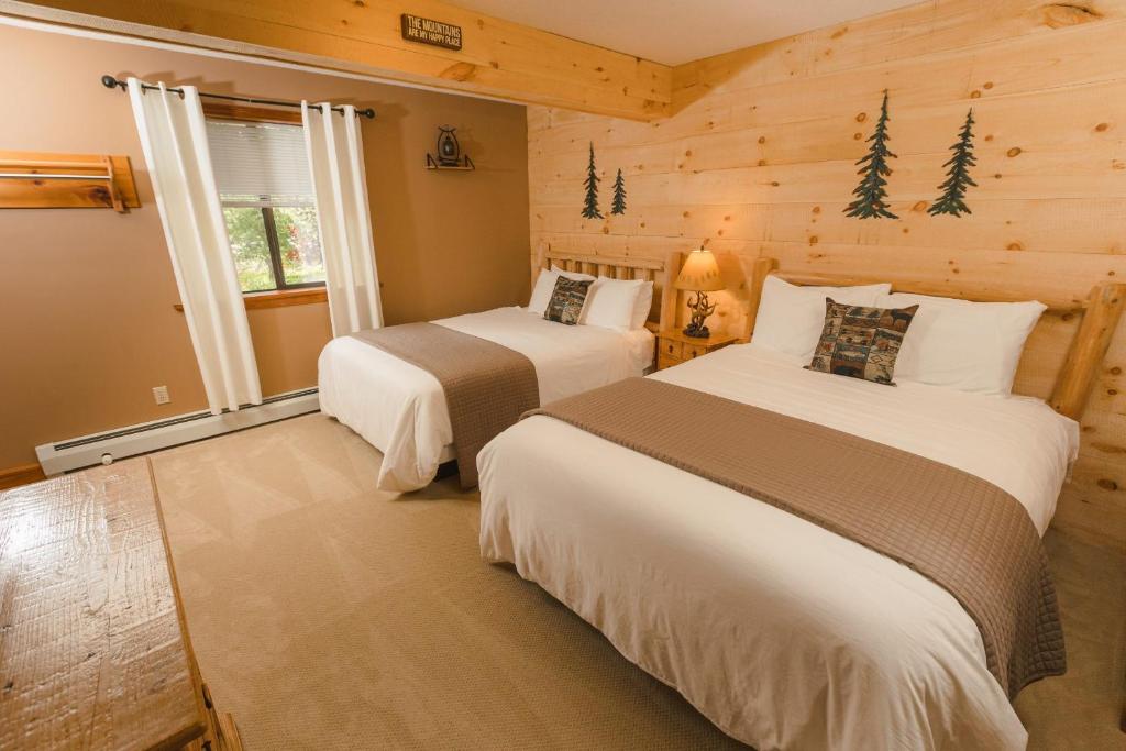 twee bedden in een kamer met houten wanden bij The Snowed Inn in Killington