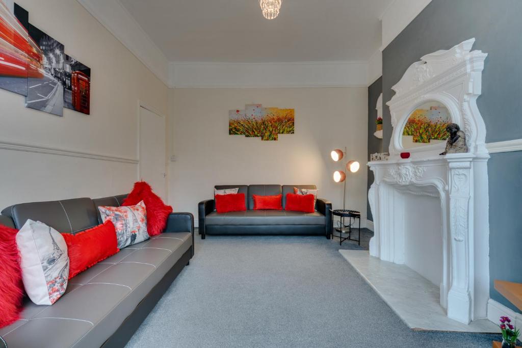 - un salon avec un canapé gris et des oreillers rouges dans l'établissement Hull Large 4 Bedrooms 8 Beds Ahenfie Plaza, à Hull