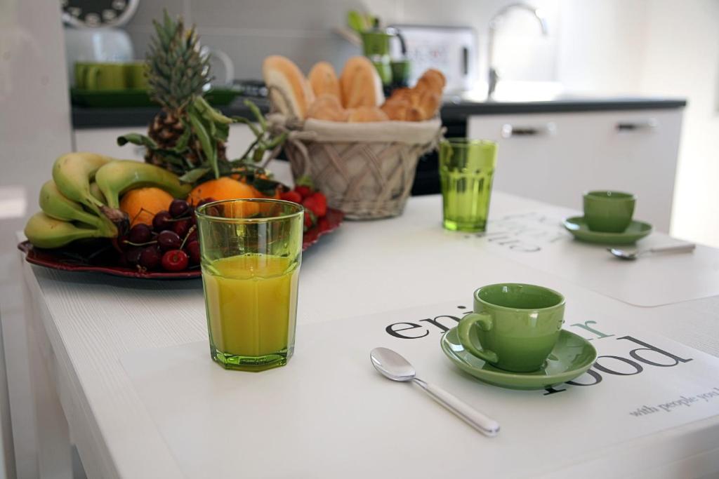 een tafel met een glas sinaasappelsap en een fruitschaal bij Car'Loft beachside in Cagliari