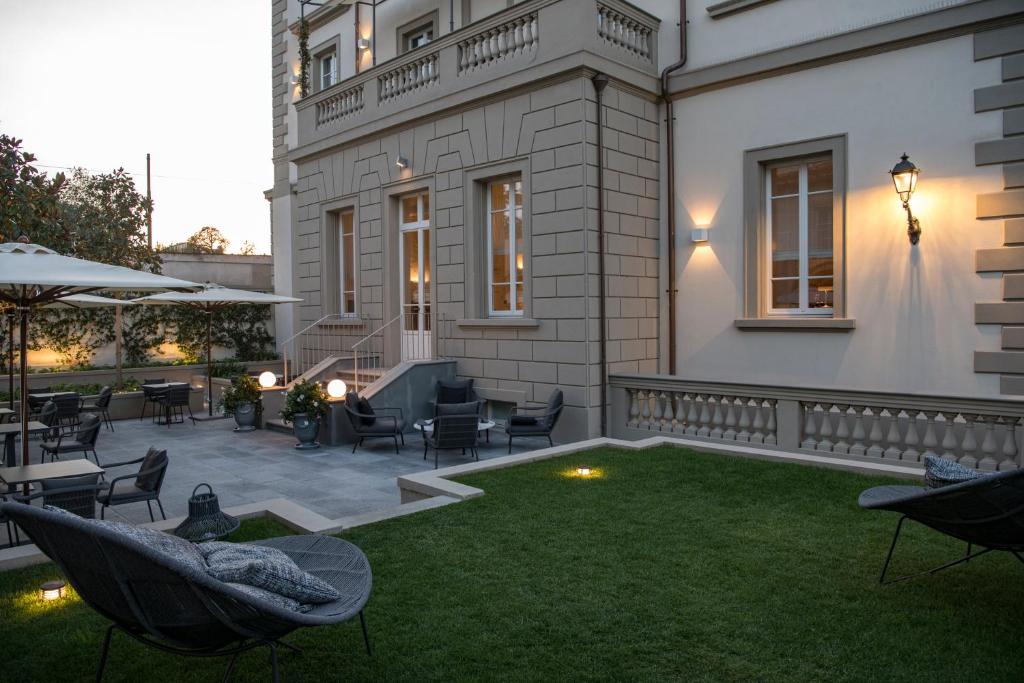 eine Terrasse mit Stühlen und Tischen auf einem Rasen in der Unterkunft Dimora Palanca in Florenz