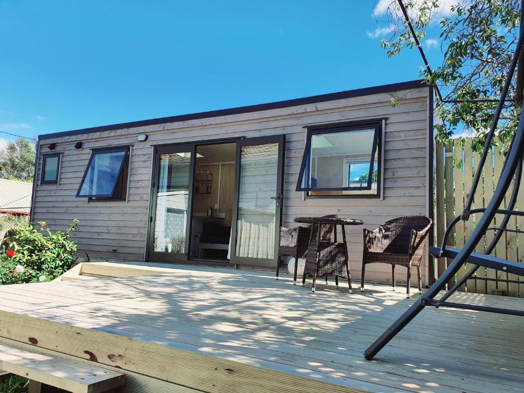 una casa pequeña con una mesa y sillas en una terraza en Dunedin Luxurious Retreat Cabin en Dunedin