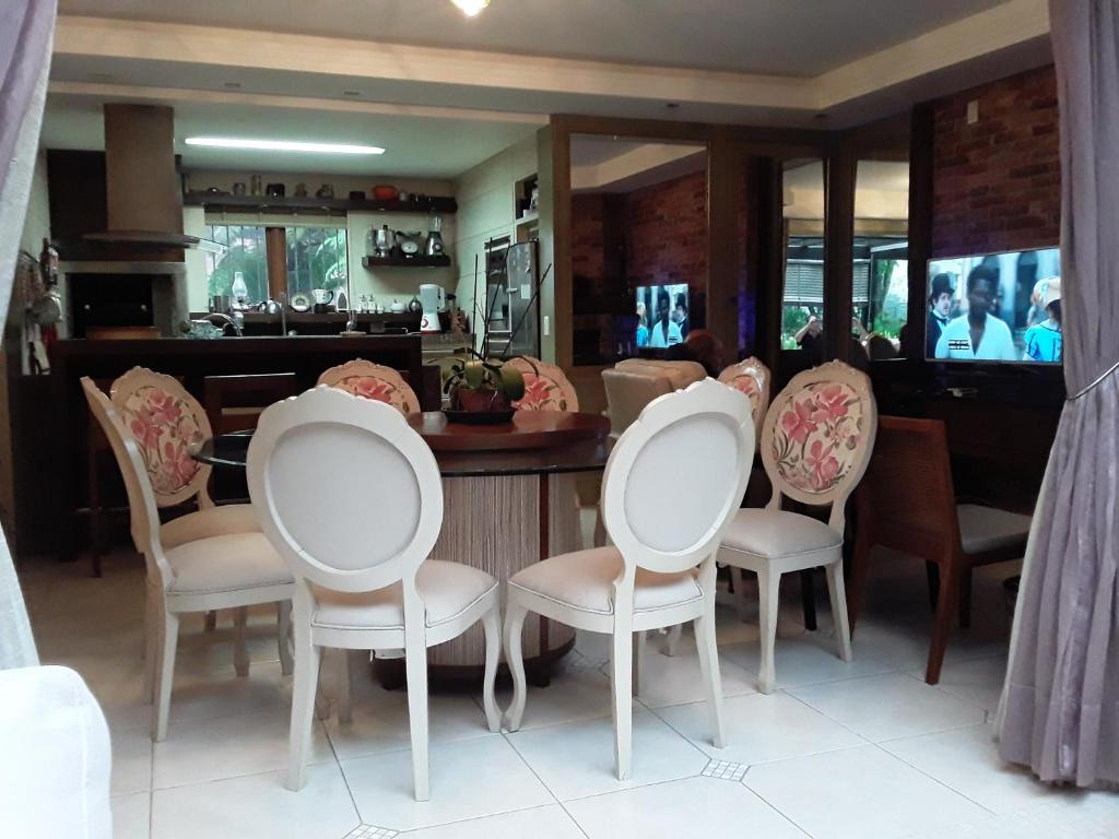 comedor con sillas blancas y mesa en Casa Planalto, en Gramado