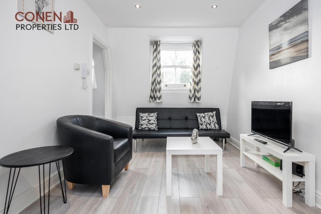 a living room with a black leather couch and a tv at CONEN Aplite Apartment in London