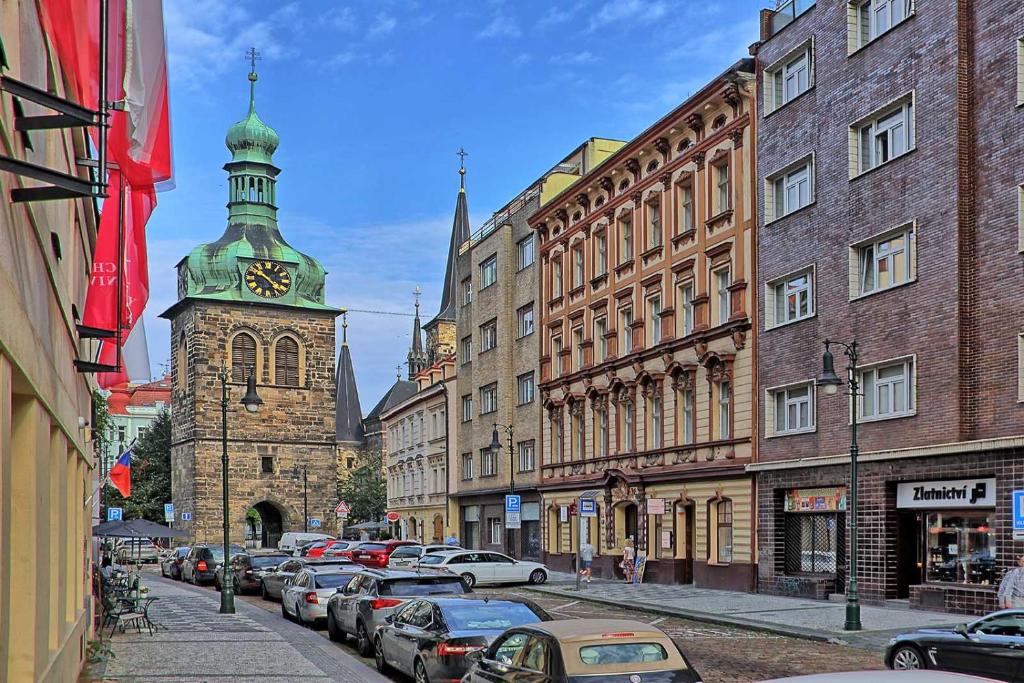 una calle de la ciudad con una torre del reloj y edificios en Peter's Tower Apartments, en Praga