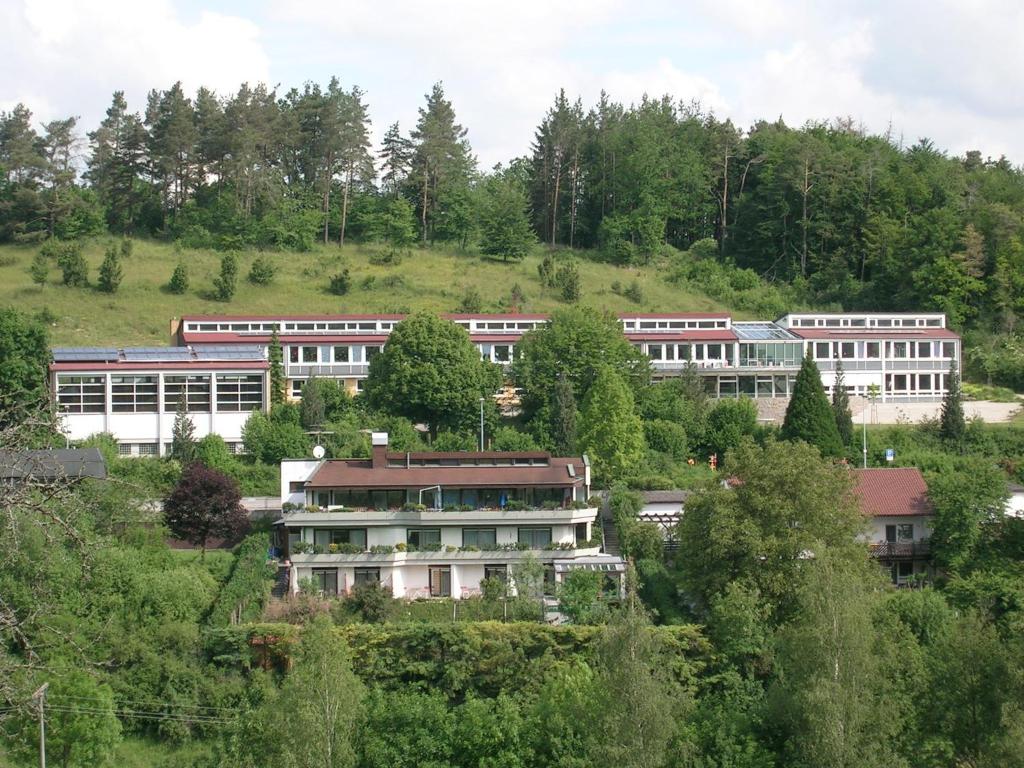 a group of buildings on a hill with trees at Pension Grasy in Aidlingen