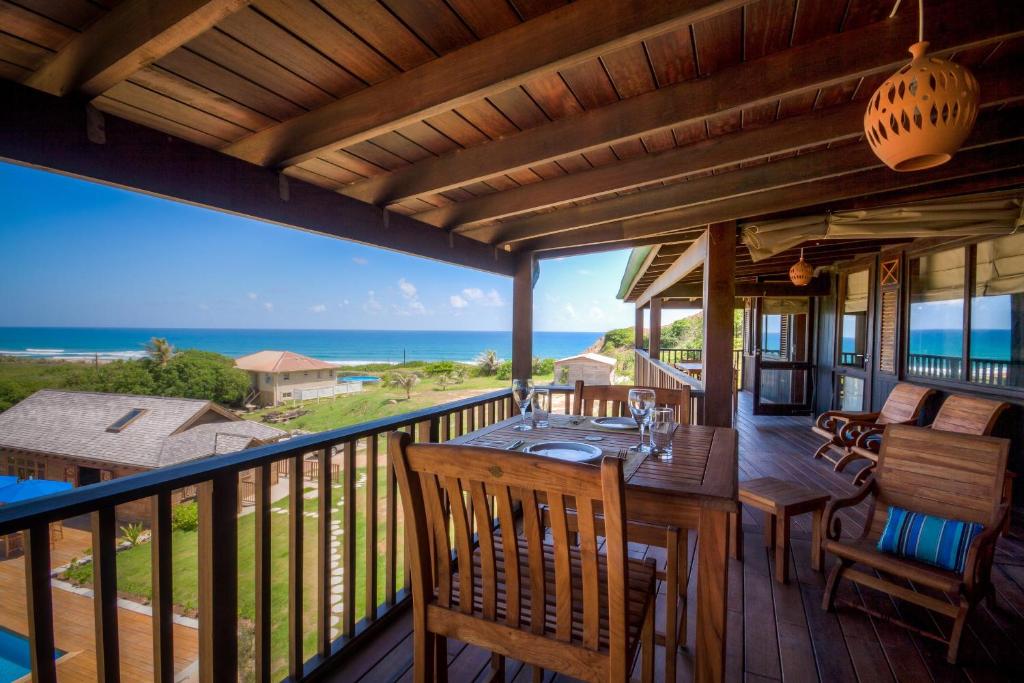 a porch with a table and chairs and the ocean at Santosha Barbados in Saint Andrew