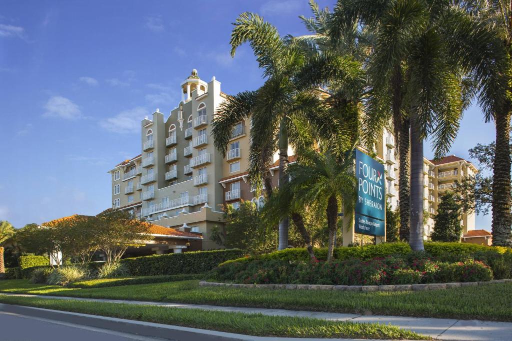 a hotel with palm trees in front of a building at Four Points by Sheraton Suites Tampa Airport Westshore in Tampa