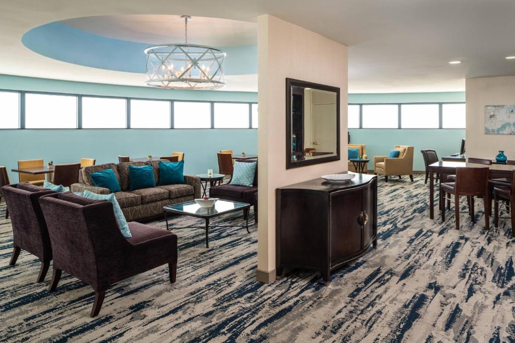 una sala de espera con sofás, sillas y espejo en Sheraton Tampa Brandon Hotel, en Tampa