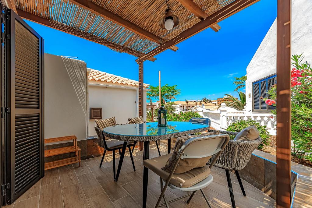 eine Außenterrasse mit einem Tisch und Stühlen in der Unterkunft Deluxe bungalow Perla Del Sur in Adeje