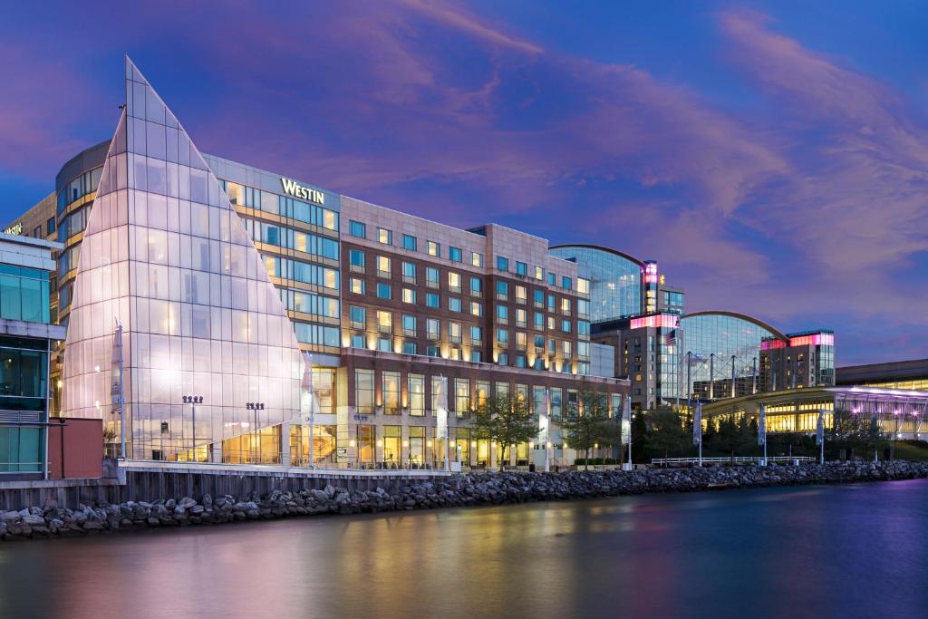 een gebouw met een glazen gevel naast een waterlichaam bij The Westin Washington National Harbor in National Harbor