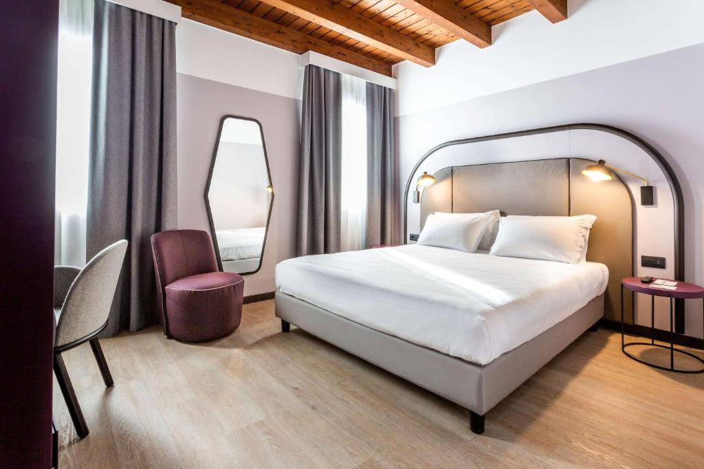 Pokój hotelowy z łóżkiem i lustrem w obiekcie BEST WESTERN Titian Inn Hotel Treviso w mieście Silea