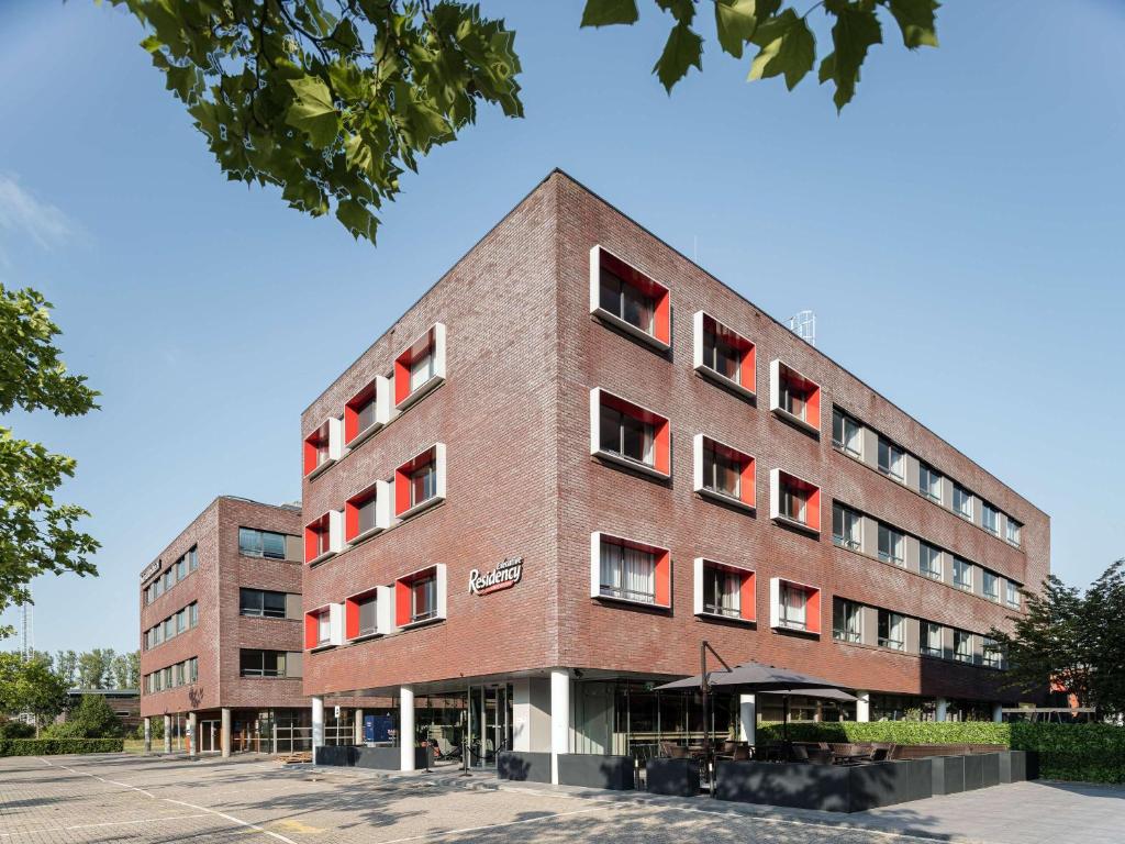 un edificio de ladrillo con ventanas rojas en un aparcamiento en Executive Residency by Best Western Amsterdam Airport en Hoofddorp