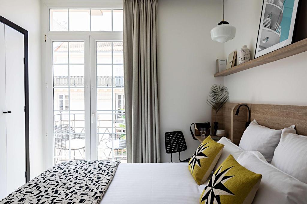 a bedroom with a bed with yellow and white pillows at Le Riviera Collection, Signature Collection by Best Western in Nice